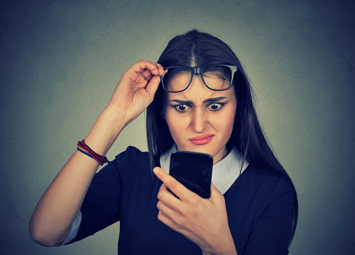 Young woman using mobile phone looking confused