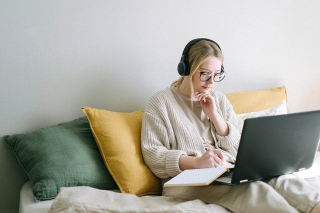 a girl takes notes as she learns from a webinar